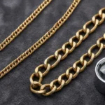 Gold chain and gold-tone costume necklace side by side with a jeweler's loupe